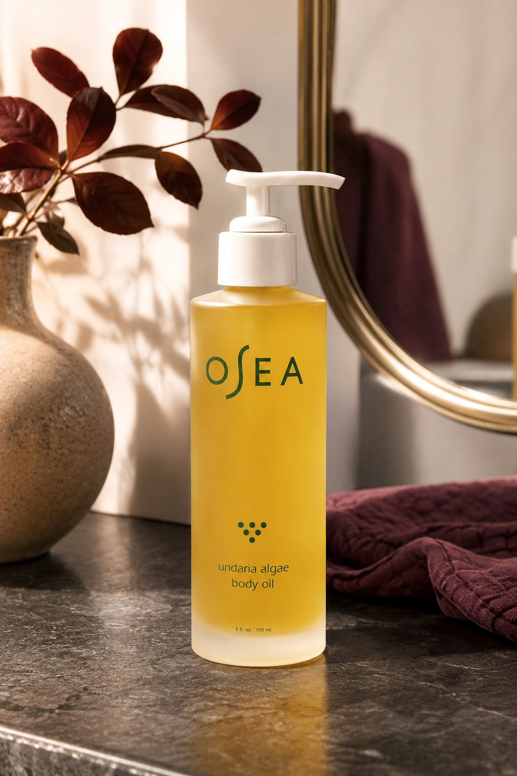 OSEA Undaria Algae Body Oil displayed on a warm stone vanity with plum accents.